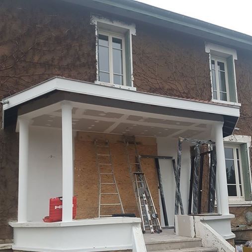 Avant les travaux : porche à colonnes blanches encore ouvert devant une maison en pierre